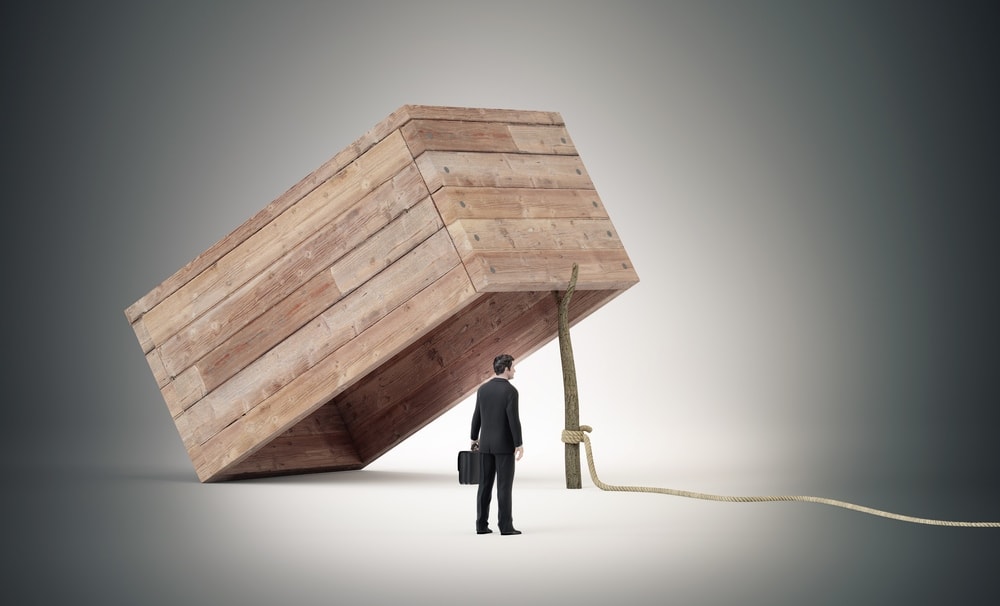 Businessman standing in front of a giant wooden trap, symbolizing the challenge of escaping the Founder’s Trap by scaling your business with strategic delegation